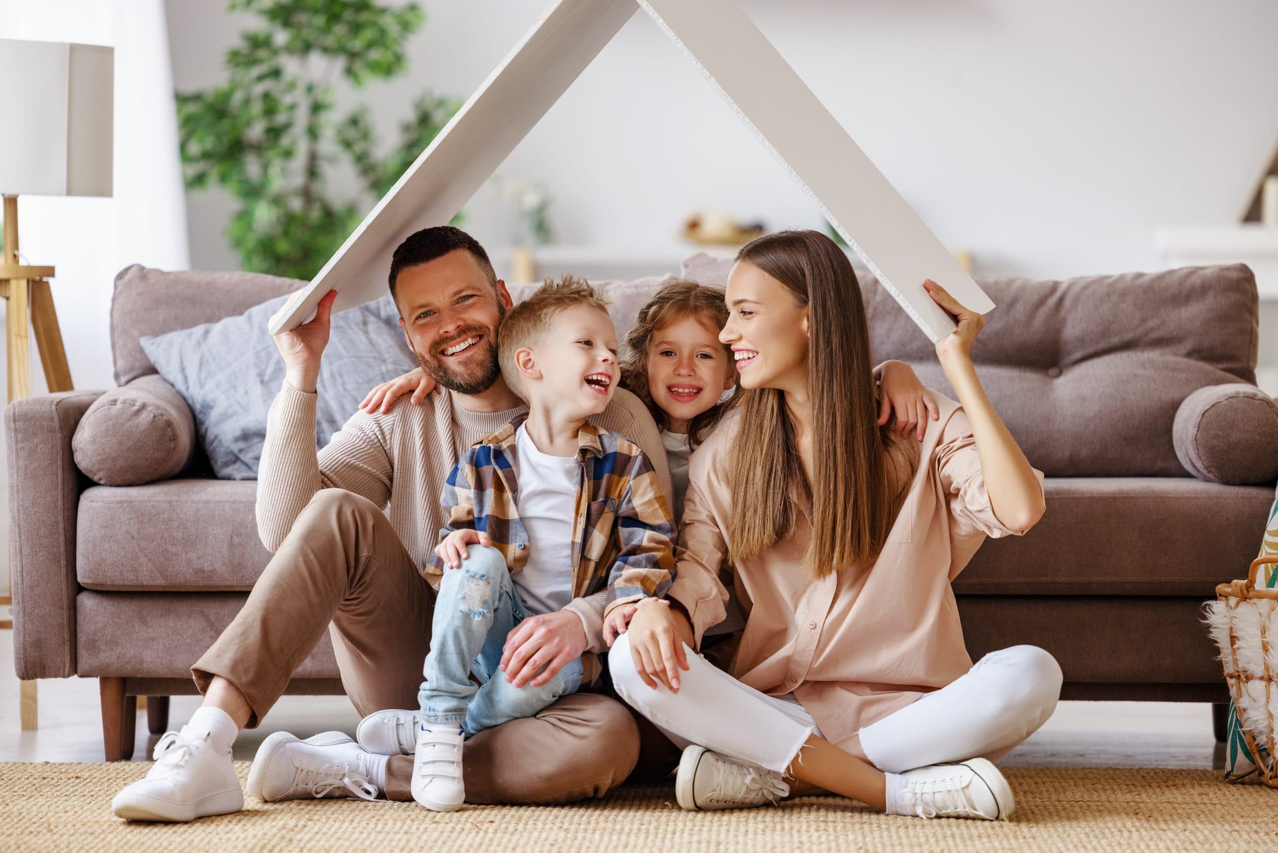 Family with two children holding a roof shape above their heads in the living room