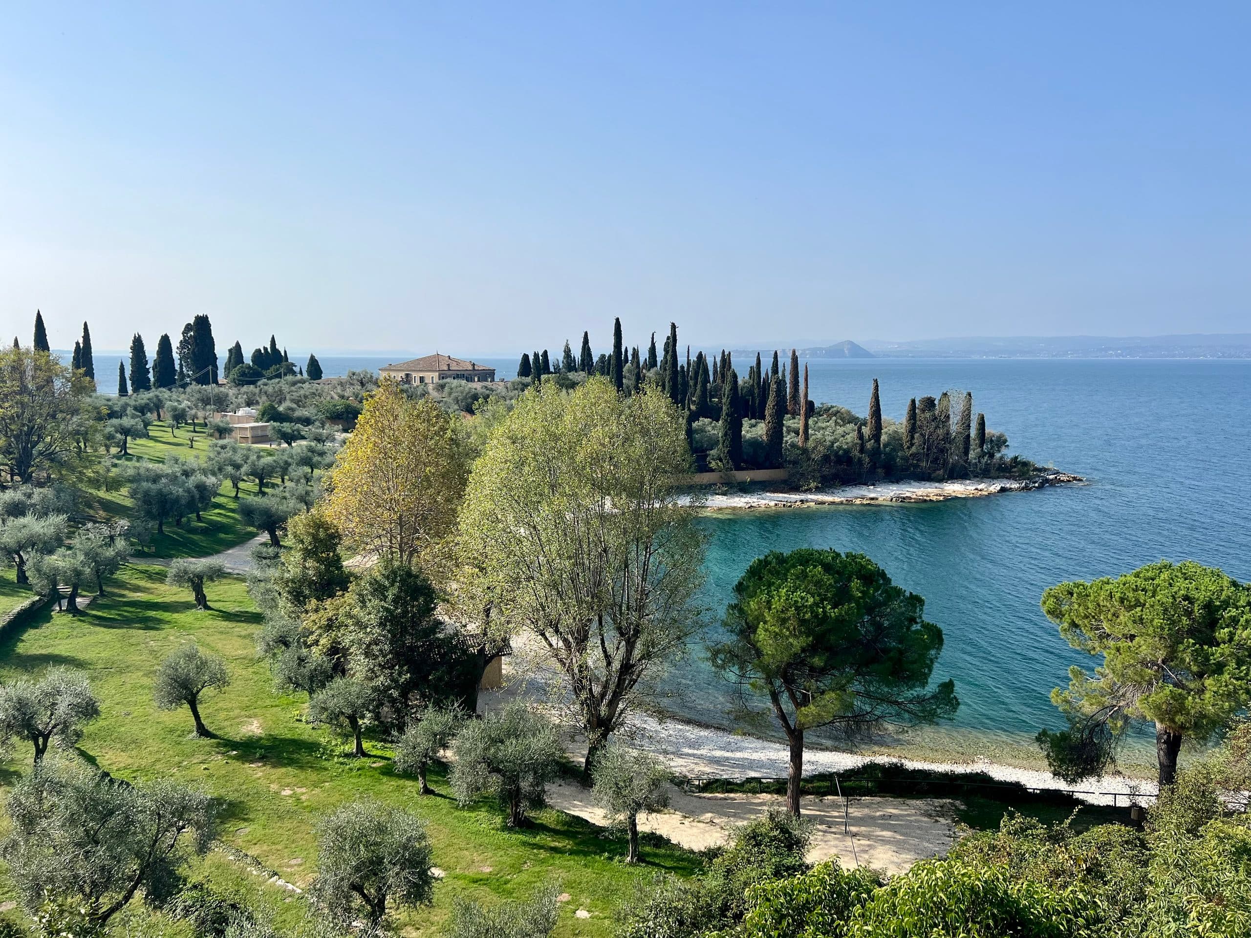 Bay on Lake Garda with an olive grove, cypresses and a villa on the headland