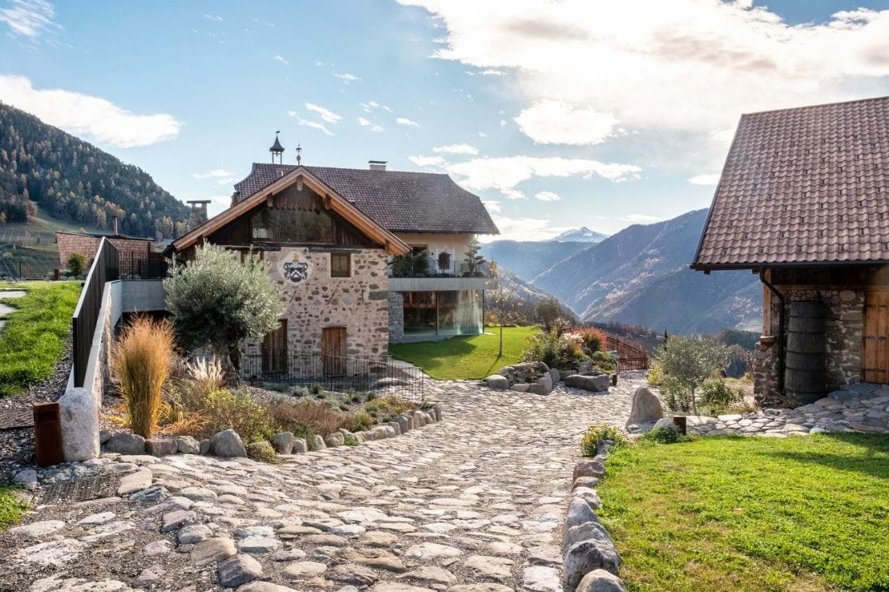 Restored South Tyrolean farmhouse of stone and wood with a cobbled path and mountain view