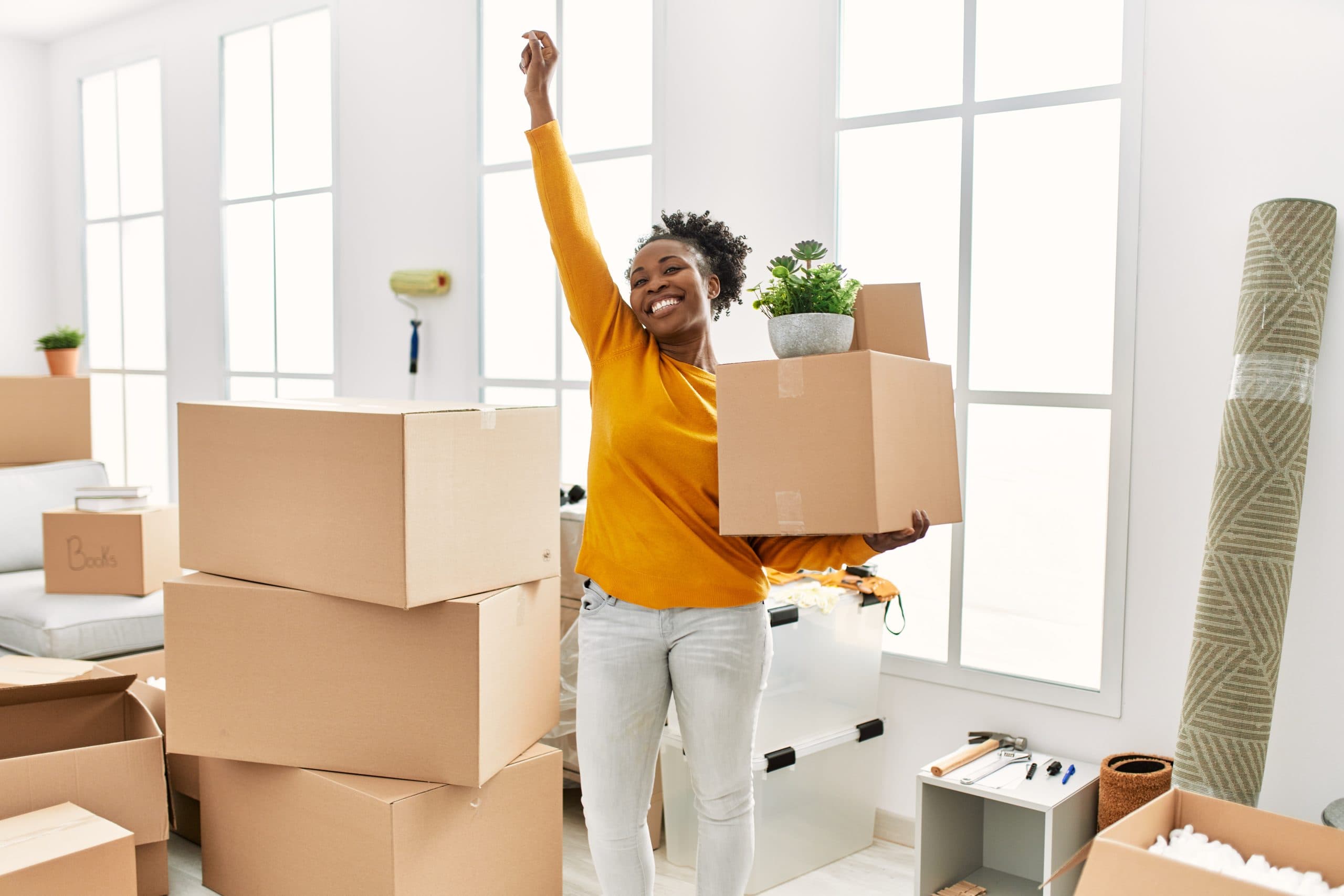 Woman celebrating with a moving box in her empty new rented flat